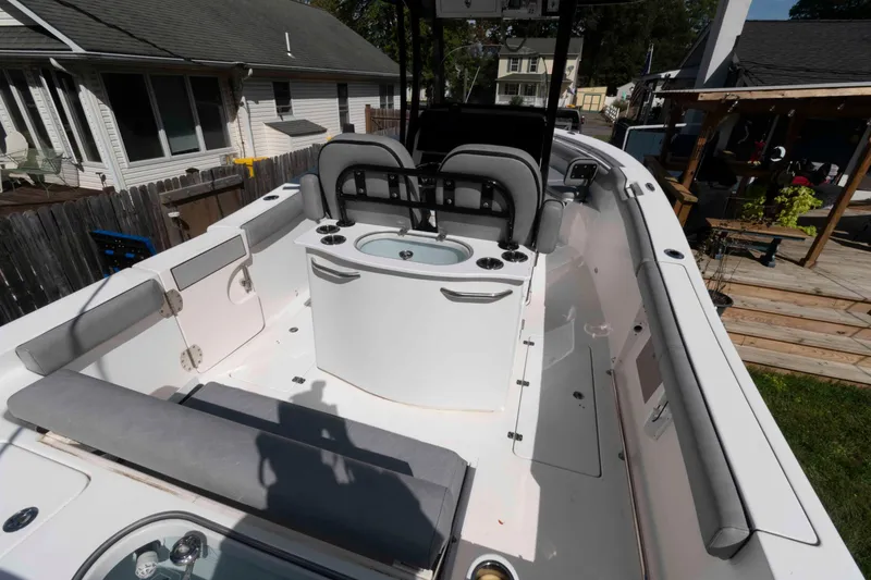 Slide: The Image of 2020 Sea Pro 259 Center Console boat interior with seating and storage, docked near houses. - 3