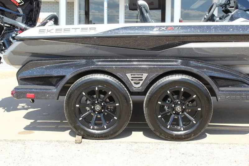 Slide: The Image of 2026 Skeeter FXR21 FLEX boat trailer with black alloy wheels and sleek design. - 6