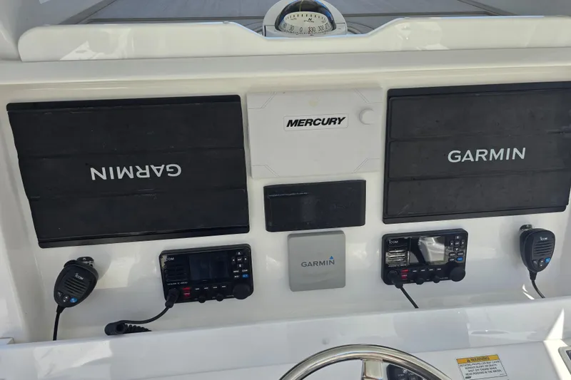 Slide: The Image of 2022 Invincible 33 Catamaran dashboard with Garmin and Mercury electronics, featuring Icom communication devices. - 20