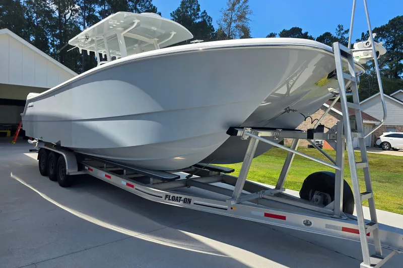 Slide: The Image of 2022 Invincible 33 Catamaran on trailer, parked outdoors in a residential area. - 8