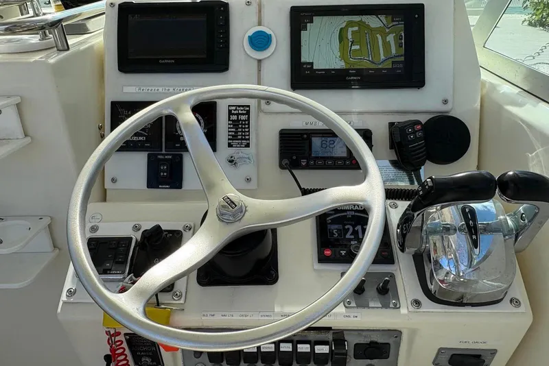 Slide: The Image of Control panel of a 2001 Pursuit 2870 Walkaround boat with steering wheel and navigation equipment. - 11