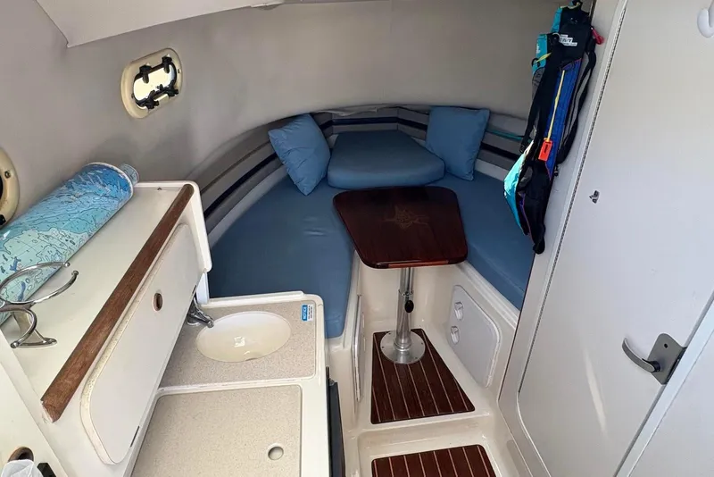 Slide: The Image of 2001 Pursuit 2870 Walkaround cabin interior with seating, table, and compact sink area. - 24