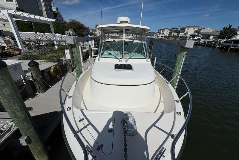 Slide: The Image of 2001 Pursuit 2870 Walkaround boat docked at a marina, surrounded by waterfront homes. - 34