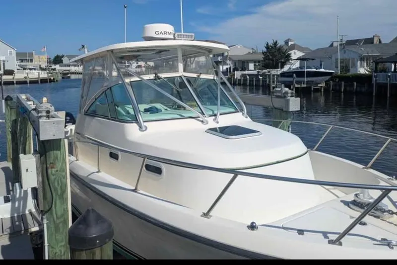 Slide: The Image of 2001 Pursuit 2870 Walkaround boat docked in a marina under clear skies. - 4