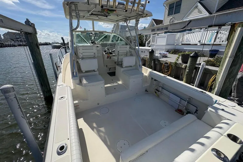 Slide: The Image of 2001 Pursuit 2870 Walkaround boat docked, featuring spacious deck and seating area. - 5