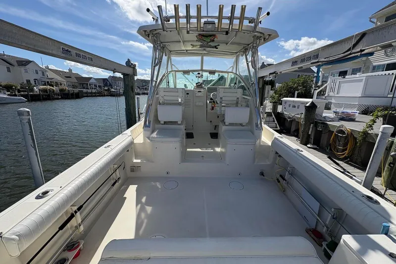 Slide: The Image of 2001 Pursuit 2870 Walkaround boat docked, featuring spacious deck and seating under clear blue sky. - 7