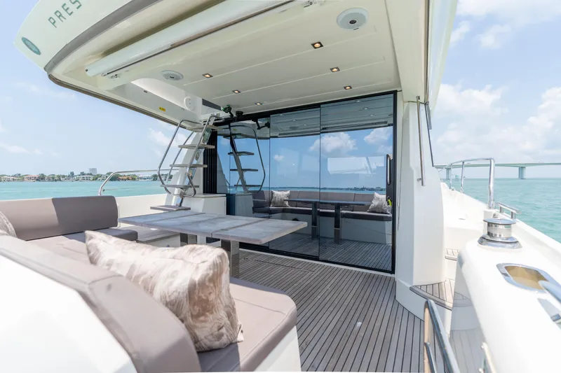 Slide: The Image of Prestige 520 Flybridge 2019 yacht with outdoor seating and dining area, city skyline in background. - 29