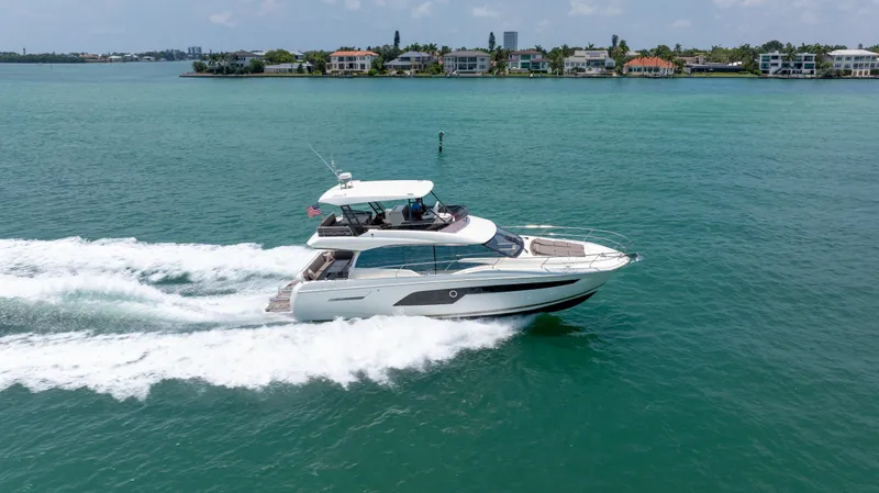 Slide: The Image of 2019 Prestige 520 Flybridge yacht cruising on a sunny day near coastal homes. - 3