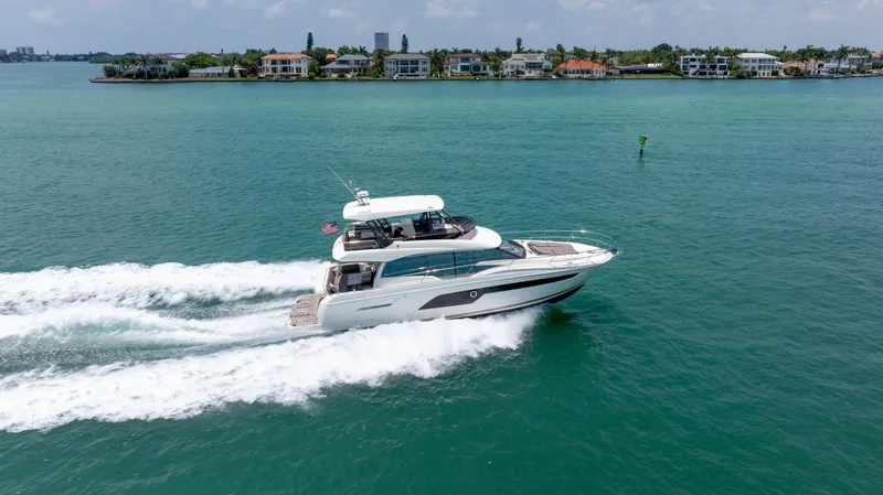 Slide: The Image of 2019 Prestige 520 Flybridge yacht cruising on a sunny day near coastal homes. - 46