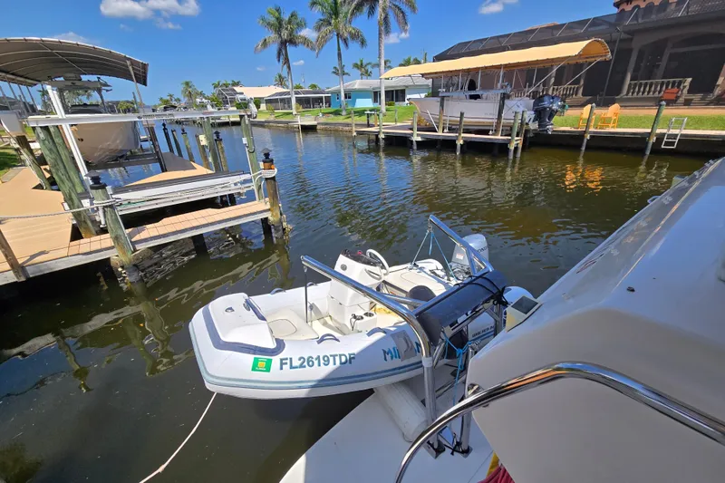 Slide: The Image of 2004 Sea Ray 480 Motor Yacht docked with small boat, palm trees, and clear sky. - 25
