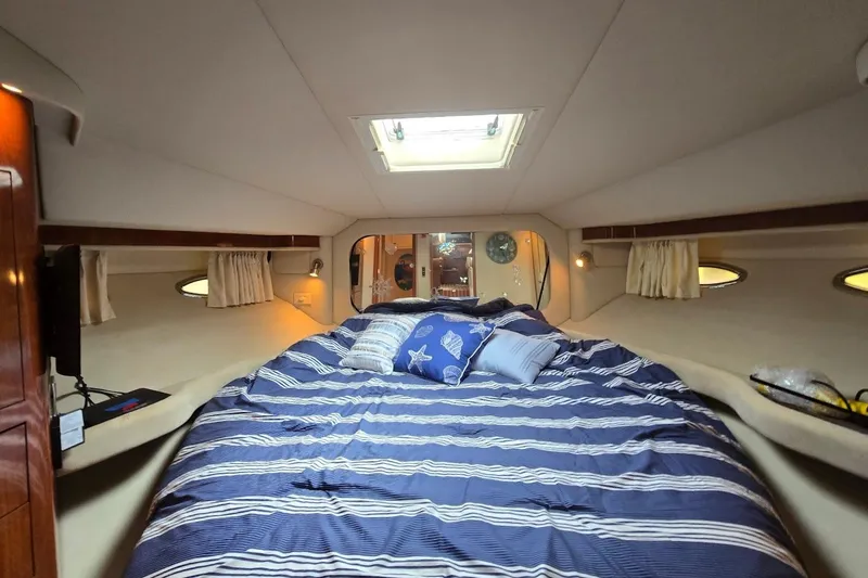 Slide: The Image of Luxurious 2004 Sea Ray 480 Motor Yacht bedroom with striped bedding and cozy lighting. - 33