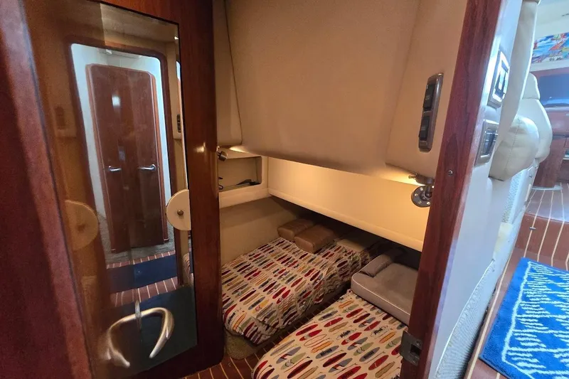 Slide: The Image of 2004 Sea Ray 480 Motor Yacht interior with cozy twin beds and wooden accents. - 34