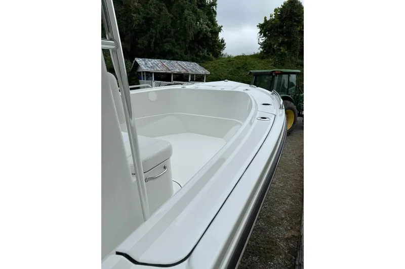 Slide: The Image of 2026 Parker 210 Coastal boat with T-top and helm seating, docked outdoors. - 2