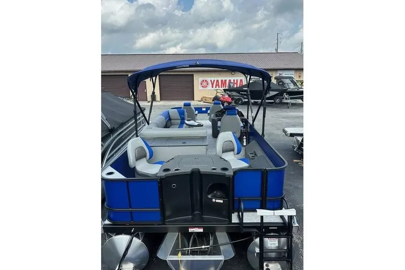 Slide: The Image of 2026 Bennington 23 SF Family boat with blue seating and canopy, parked outdoors. - 38