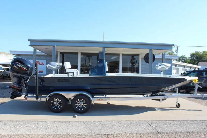The Image of 2026 Excel Bay Pro Elite 220 boat on trailer, parked outside dealership. - 1