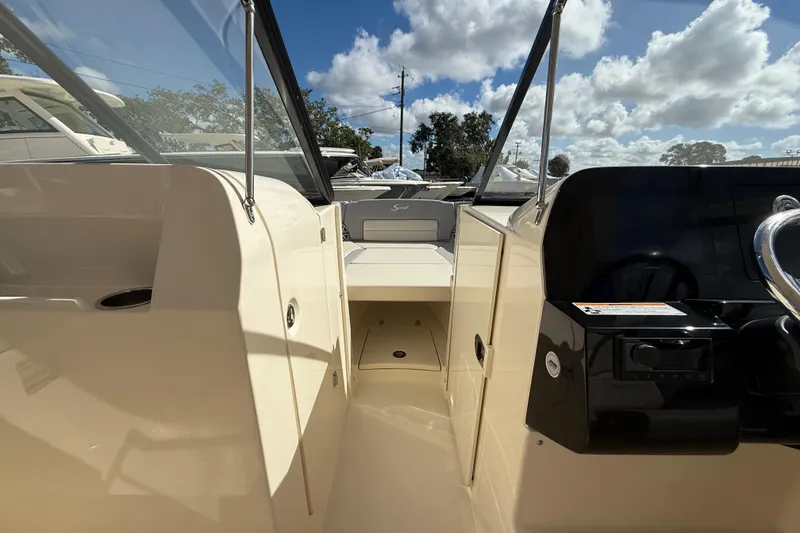 Slide: The Image of 2026 Scout 255 Dorado boat interior with steering wheel and seating under a blue sky. - 22
