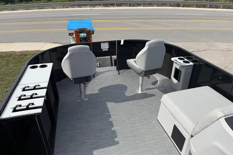 Slide: The Image of 2026 Lowe LF 214 boat interior with seating and storage, parked near a road. - 9