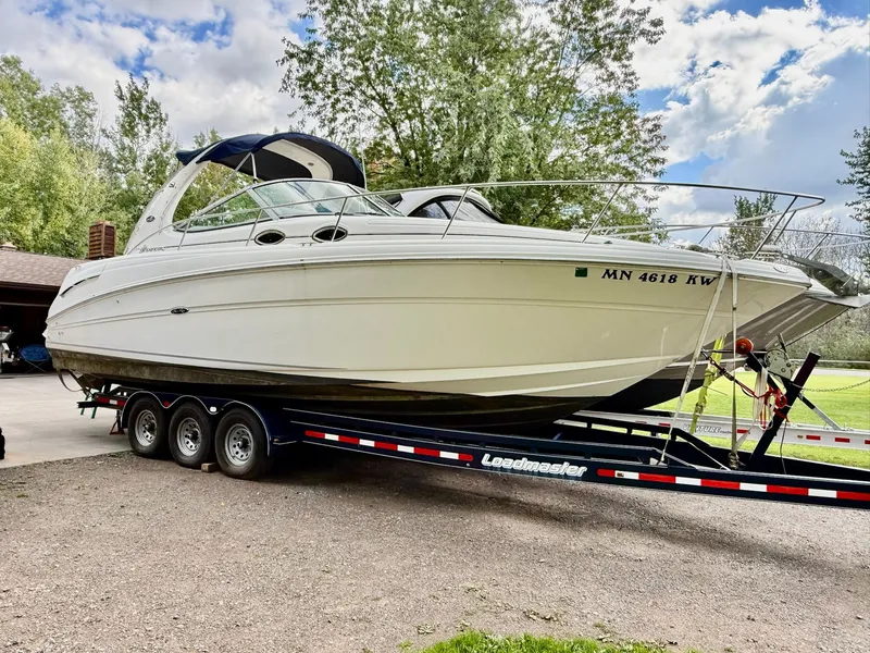 The Image of 2004 Sea Ray 300 Sundancer on trailer, parked outdoors with trees in background. - 0