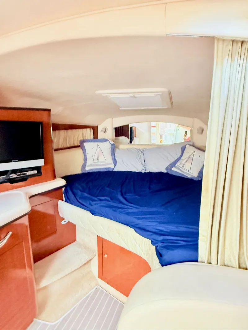 Slide: The Image of 2004 Sea Ray 300 Sundancer cabin with bed, TV, and nautical decor. - 11
