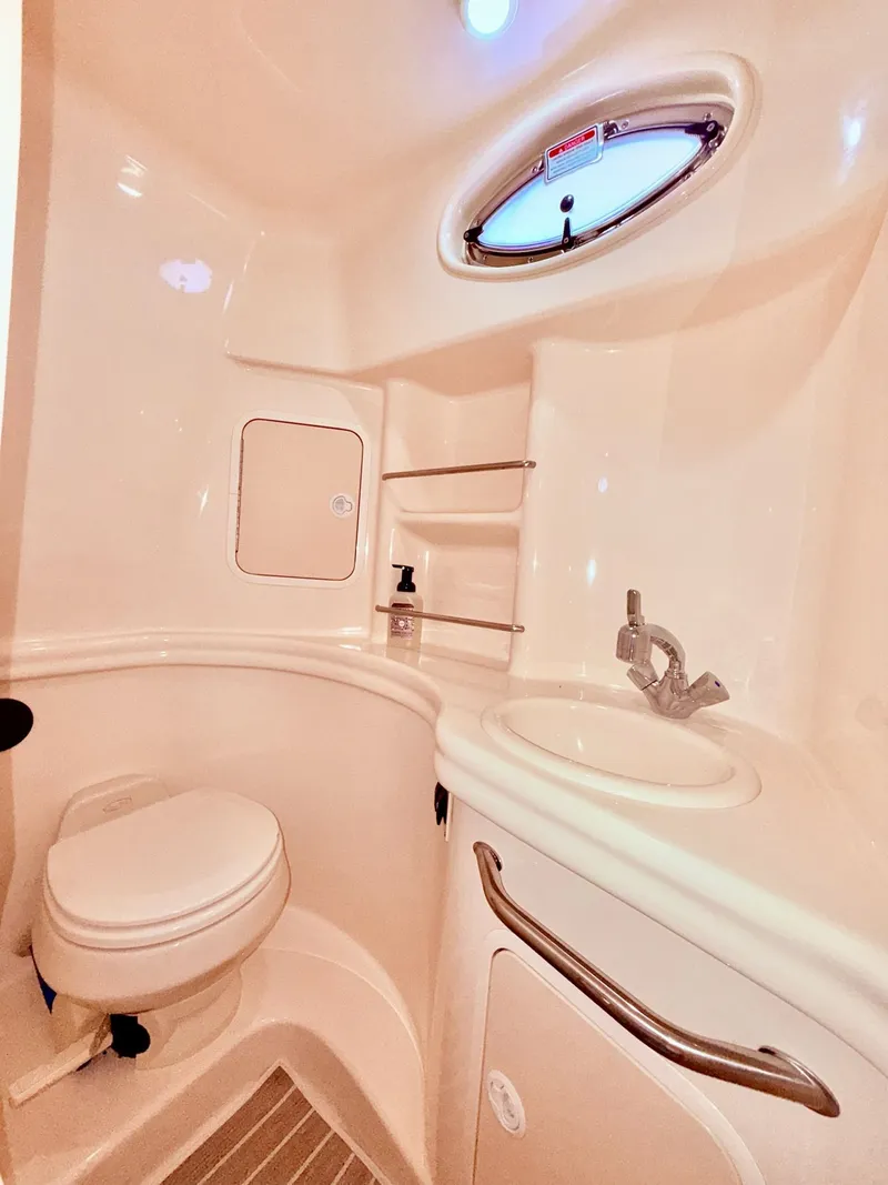 Slide: The Image of 2004 Sea Ray 300 Sundancer bathroom with sink, toilet, and porthole window. - 13