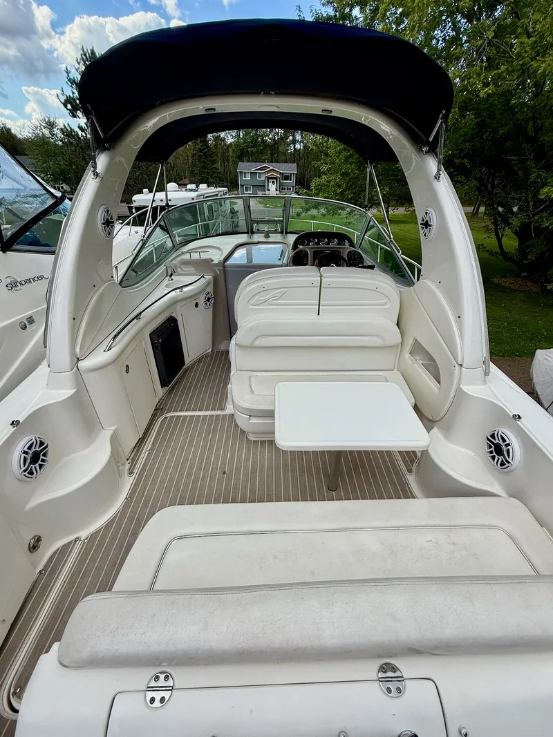 Slide: The Image of 2004 Sea Ray 300 Sundancer boat interior with seating and table, surrounded by lush greenery. - 4
