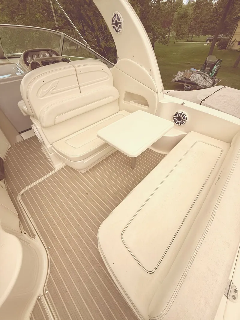 Slide: The Image of 2004 Sea Ray 300 Sundancer interior with seating and table, featuring beige upholstery and striped flooring. - 7