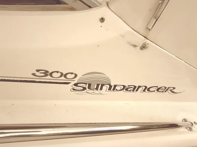 Slide: The Image of 2004 Sea Ray 300 Sundancer boat logo on white surface with chrome railing. - 9