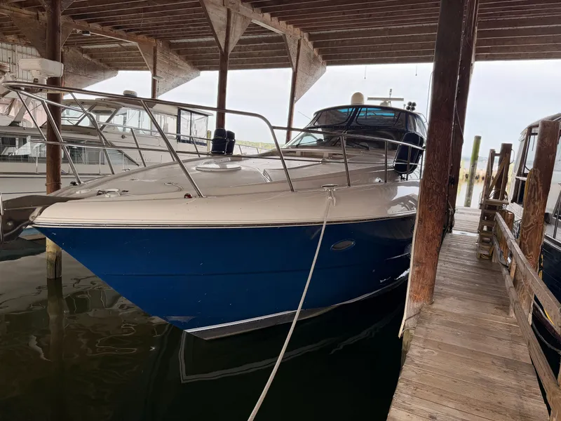 Slide: The Image of 2006 Cruisers Yachts 560 Express docked under wooden shelter. - 1