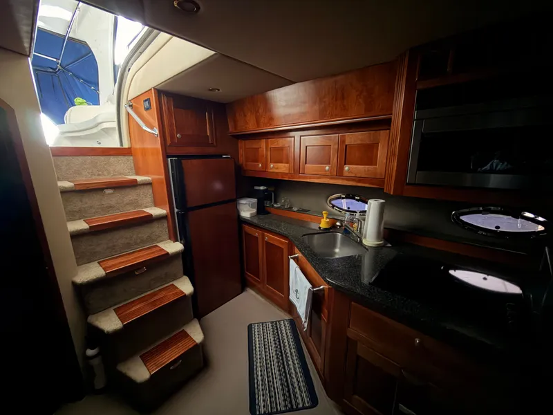 Slide: The Image of Luxurious 2006 Cruisers Yachts 560 Express interior kitchen with wood cabinetry and modern appliances. - 15