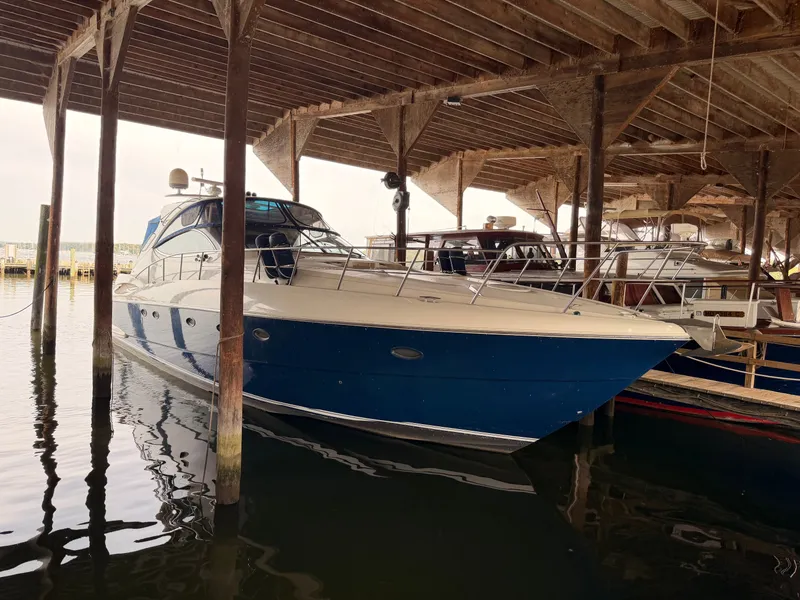 The Image of 2006 Cruisers Yachts 560 Express docked under wooden shelter. - 0