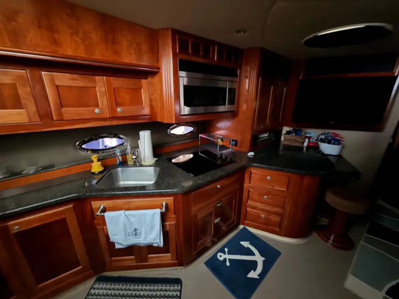 Slide: The Image of 2006 Cruisers Yachts 560 Express kitchen with wooden cabinets and modern appliances. - 14