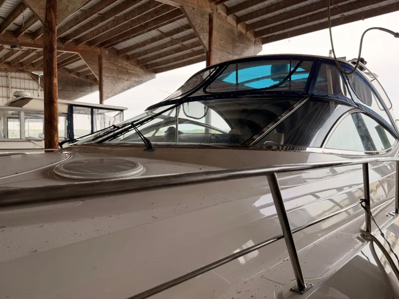 Slide: The Image of 2006 Cruisers Yachts 560 Express docked under a wooden shelter. - 2