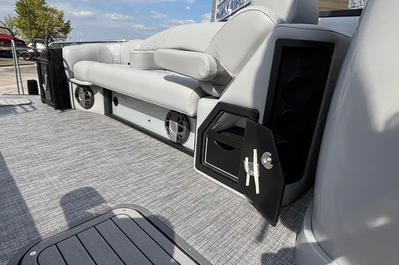 Slide: The Image of 2026 JC Sporttoon 26TT boat interior with gray seating and built-in speakers. - 26