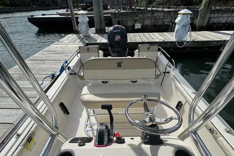Slide: The Image of 2021 Carolina Skiff 21 LS boat interior at dock, featuring steering wheel and seating. - 11
