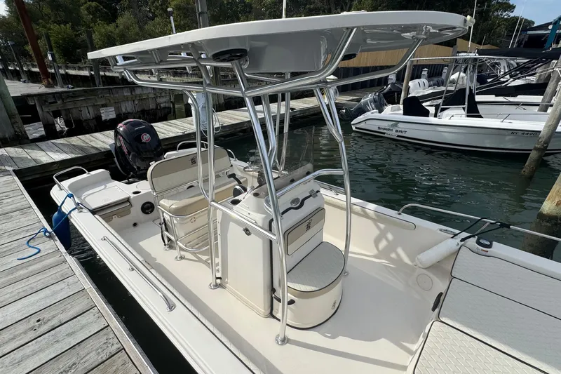 Slide: The Image of 2021 Carolina Skiff 21 LS boat docked, featuring T-top and seating, in a marina setting. - 13