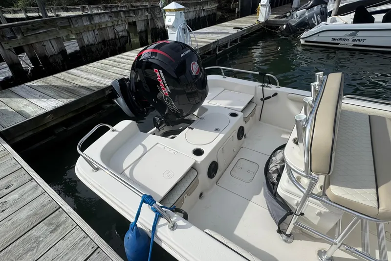 Slide: The Image of 2021 Carolina Skiff 21 LS boat docked, featuring a powerful outboard motor. - 6