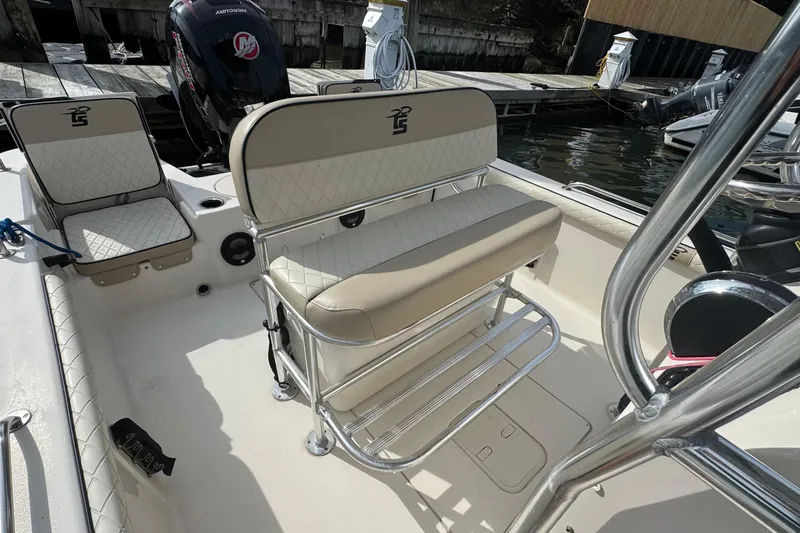 Slide: The Image of 2021 Carolina Skiff 21 LS boat interior with cushioned seating and motor at dock. - 8
