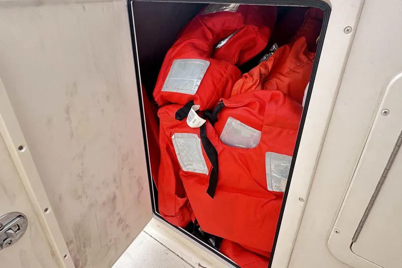 Slide: The Image of Red life jackets stored in a compartment on a 2007 Grady-White Tournament 225 boat. - 27