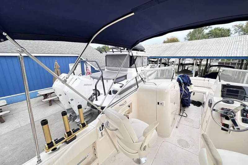 Slide: The Image of 2007 Grady-White Tournament 225 boat interior with seating and controls, docked near blue building. - 7