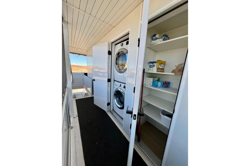 Slide: The Image of Laundry area with stacked washer-dryer and storage shelves on Adonia Aspire Trip #7, 2024. - 21