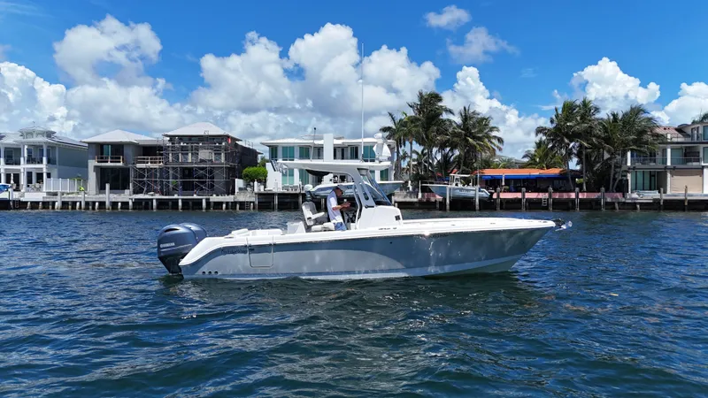 Slide: The Image of 2017 Edgewater 262CC boat cruising near waterfront homes under a clear blue sky. - 0