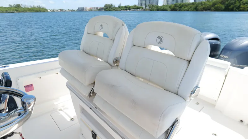 Slide: The Image of 2017 Edgewater 262CC boat with dual white cushioned seats on a sunny day. - 19