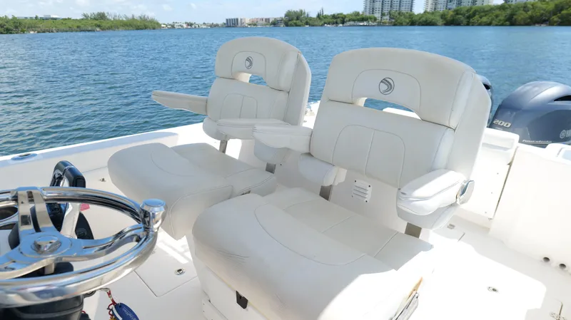 Slide: The Image of 2017 Edgewater 262CC boat interior with white seating and steering wheel, overlooking calm water. - 21
