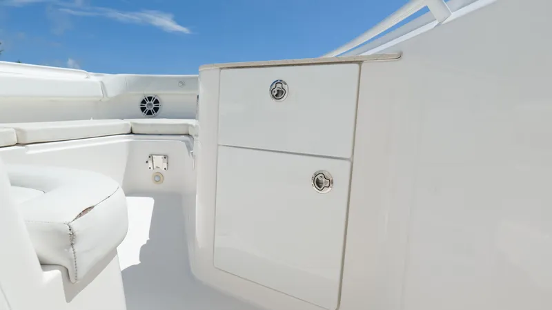 Slide: The Image of 2017 Edgewater 262CC boat interior with white seating and storage compartments under a clear blue sky. - 38