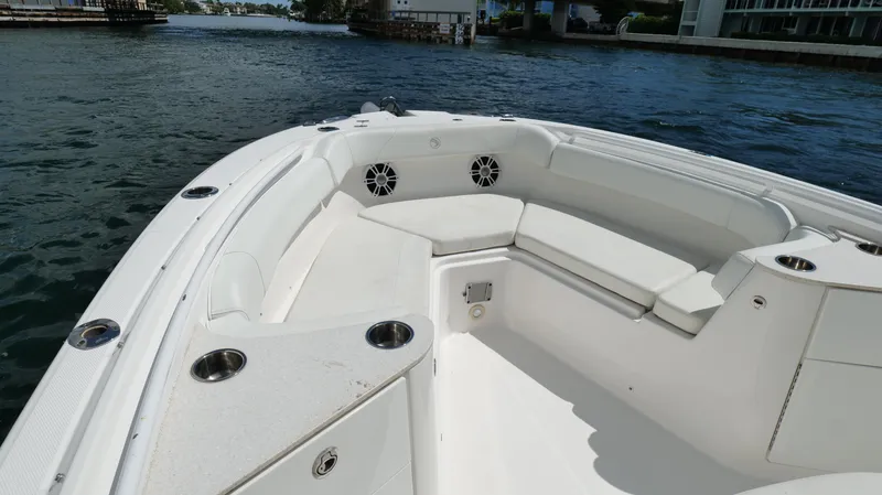 Slide: The Image of 2017 Edgewater 262CC boat interior with white seating and cup holders on calm water. - 39