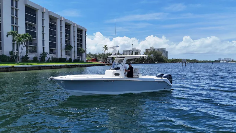 Slide: The Image of 2017 Edgewater 262CC boat cruising near waterfront buildings under a clear blue sky. - 4