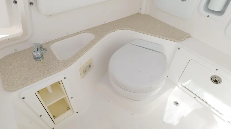 Slide: The Image of 2017 Edgewater 262CC boat interior with compact bathroom, featuring a toilet and sink. - 48
