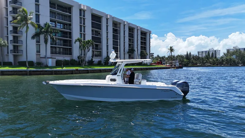 Slide: The Image of 2017 Edgewater 262CC boat cruising near waterfront buildings under a clear blue sky. - 5