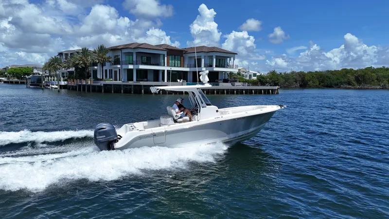 Slide: The Image of 2017 Edgewater 262CC boat cruising near luxury waterfront homes under a clear blue sky. - 55