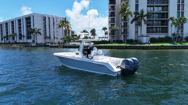 Slide: The Image of 2017 Edgewater 262CC boat cruising near waterfront buildings under a clear blue sky. - 6